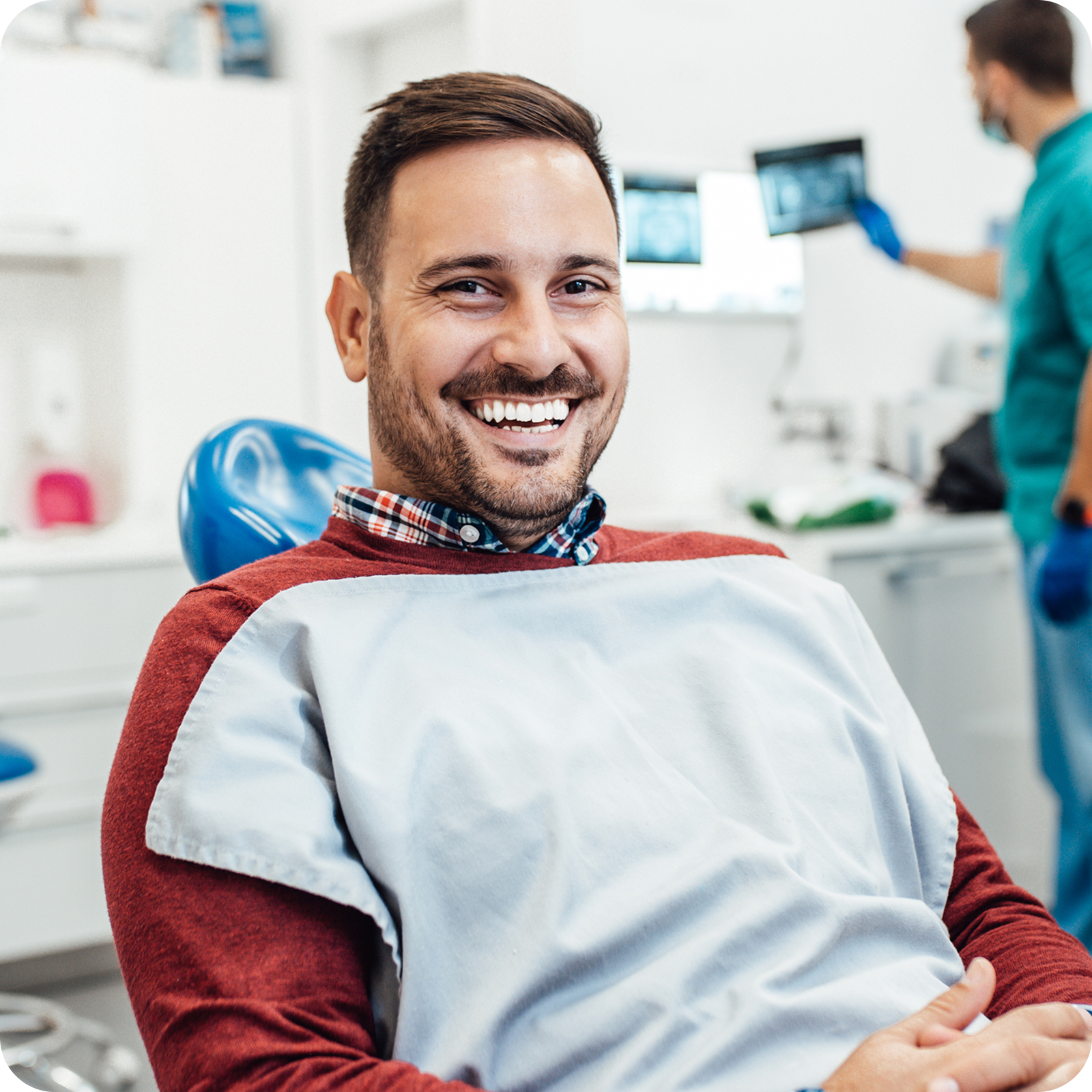 Smiling male patient relaxing in a dental chair after a successful dental appointment.